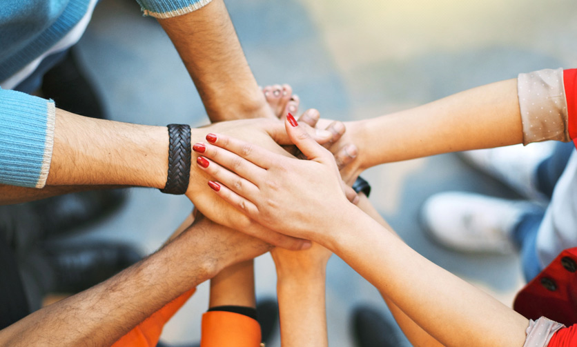 Hände übereinander symbolisieren Teamarbeit, Zusammenhalt